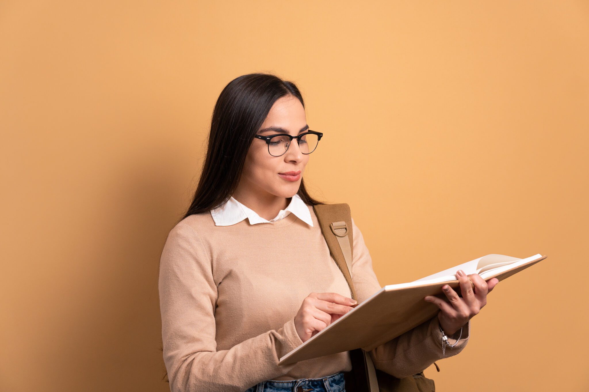 Woman reading book against plain background.